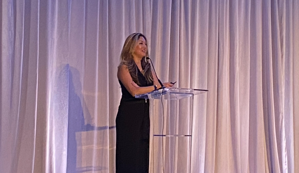 Cindy Keyes delivering keynote speech at corporate event podium